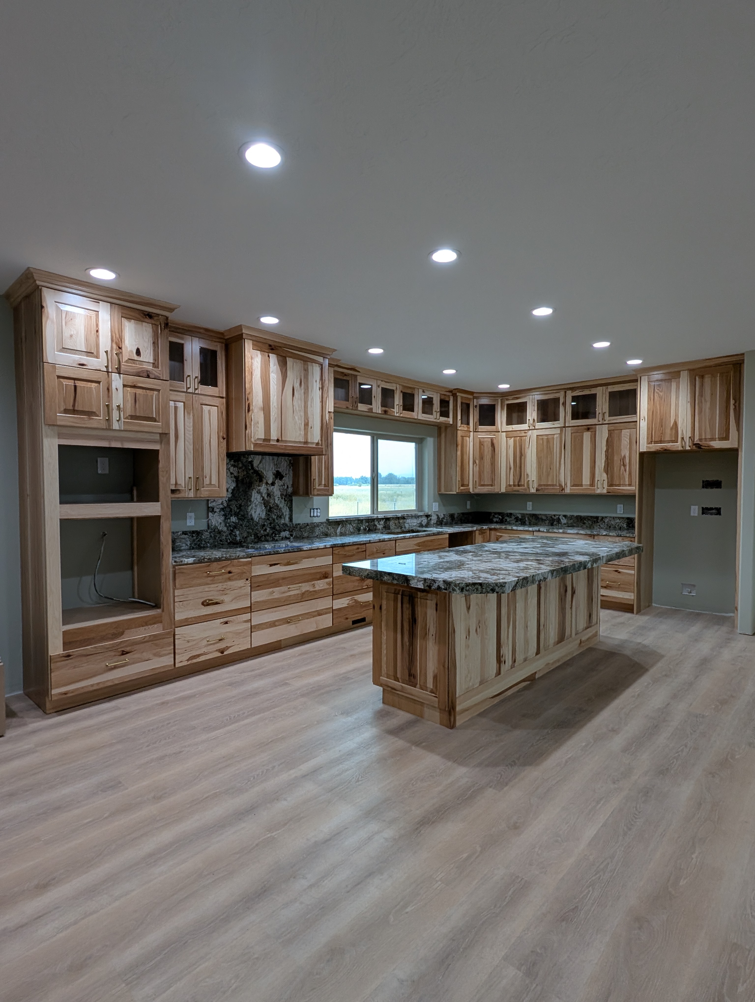 Rustic hickory kitchen with natural wood cabinetry, granite counters and a large island