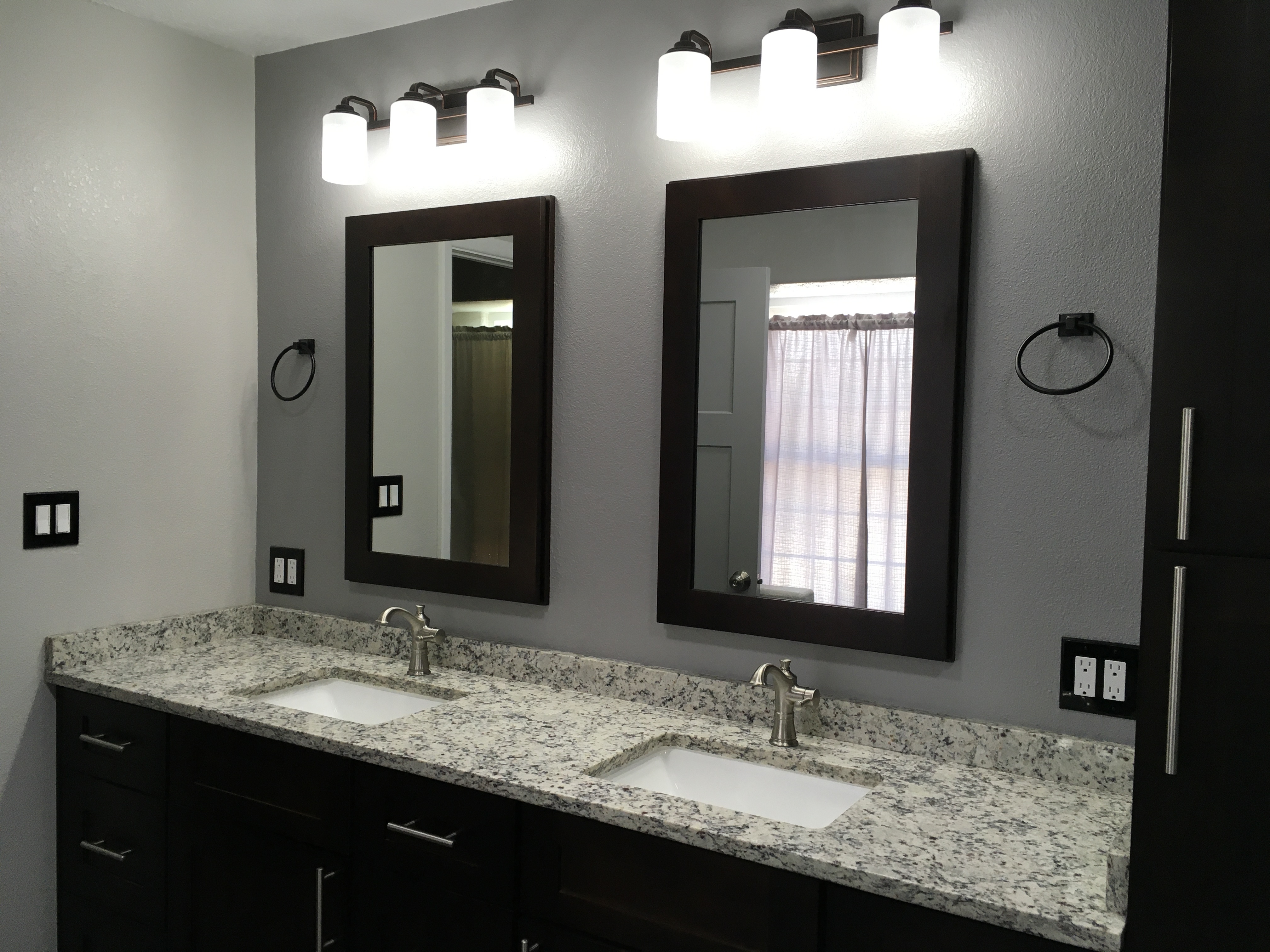 Bathroom with espresso double vanity, framed mirrors and granite countertops