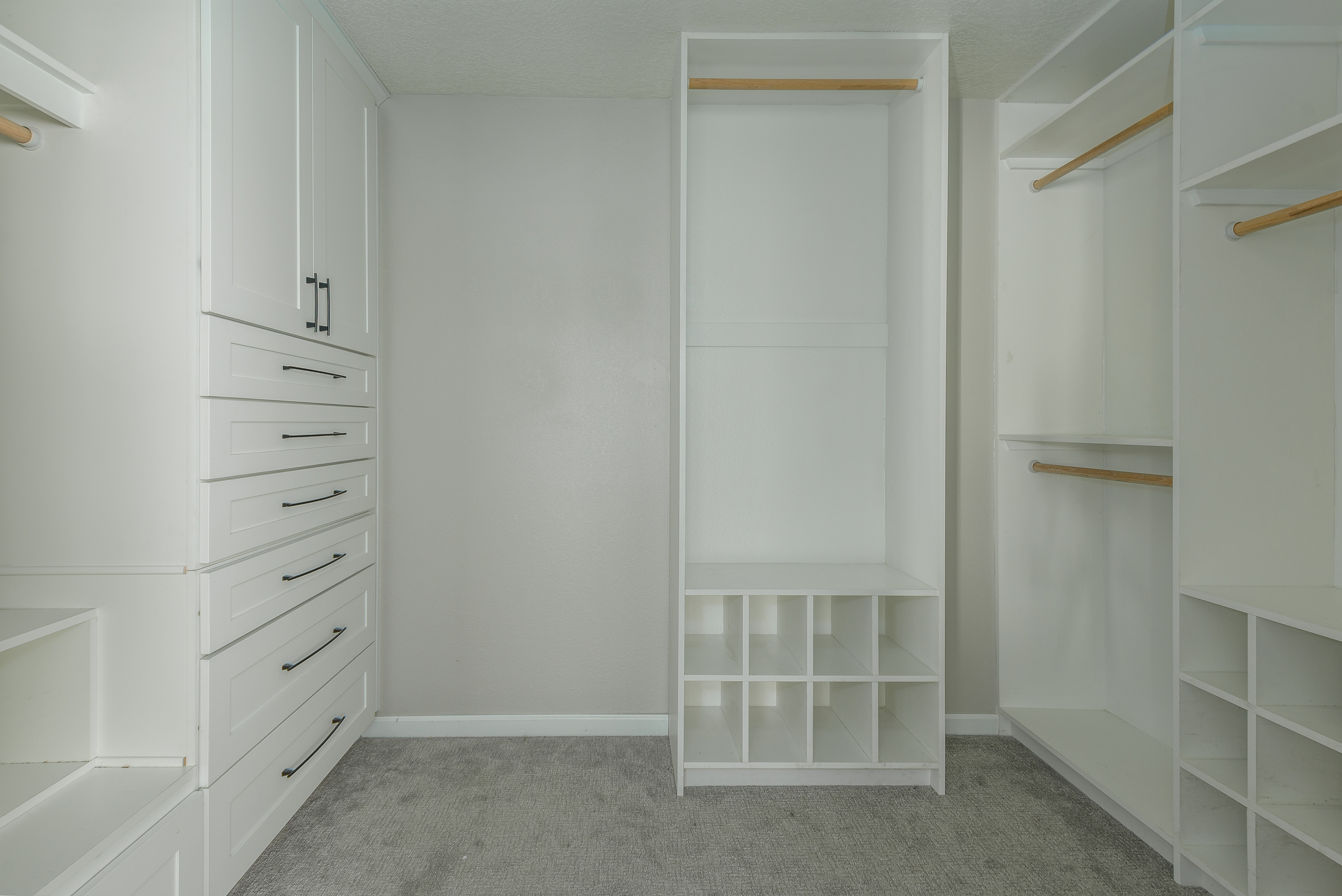 Custom white walk-in closet with built-in drawers, shelving and hanging space