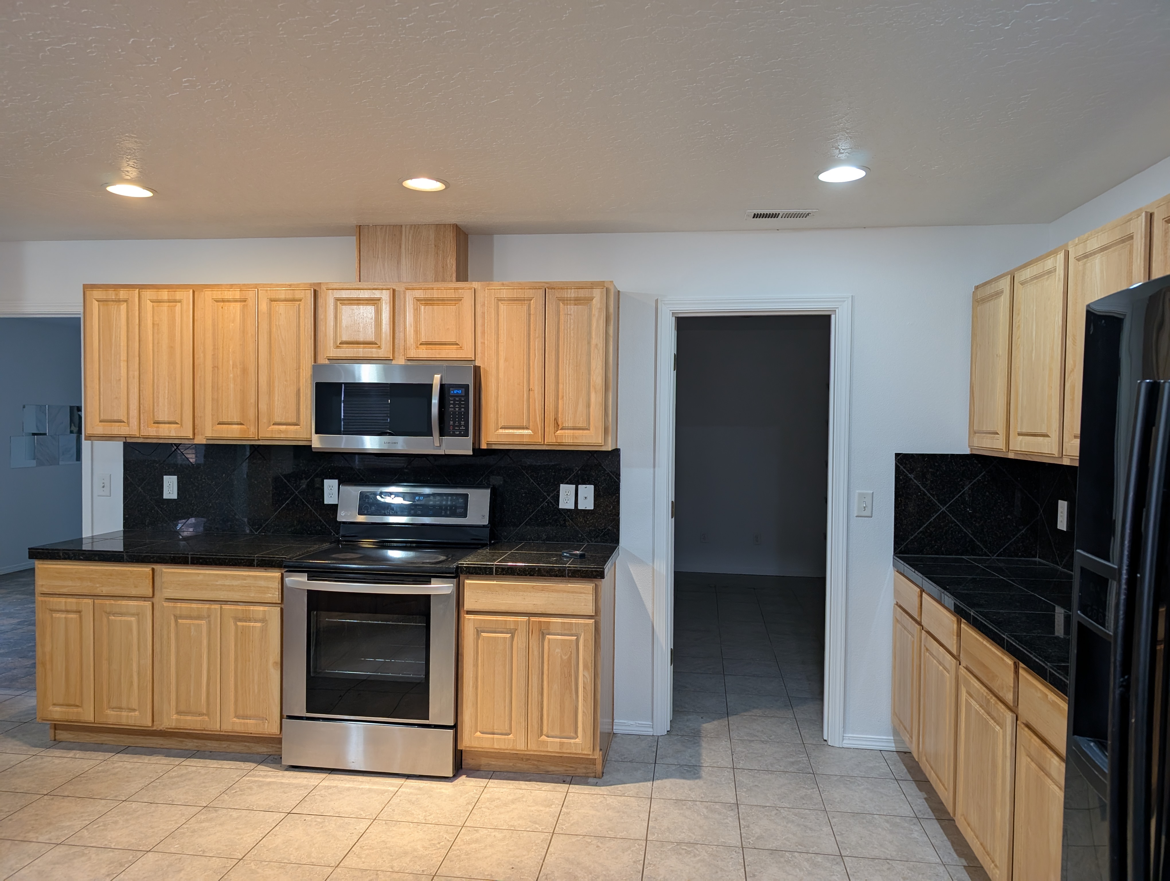 Kitchen before the remodel, with dated honey-oak cabinets and black tile counters