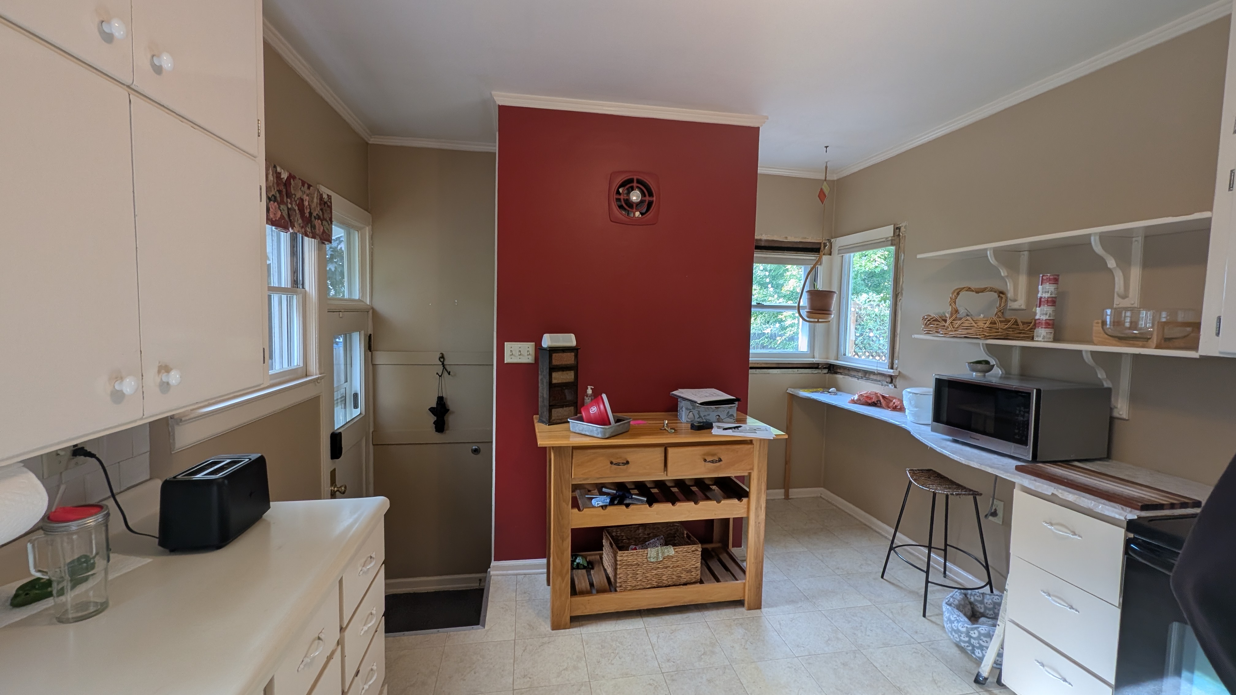 Dated kitchen with dark red accent wall and mismatched island before remodel
