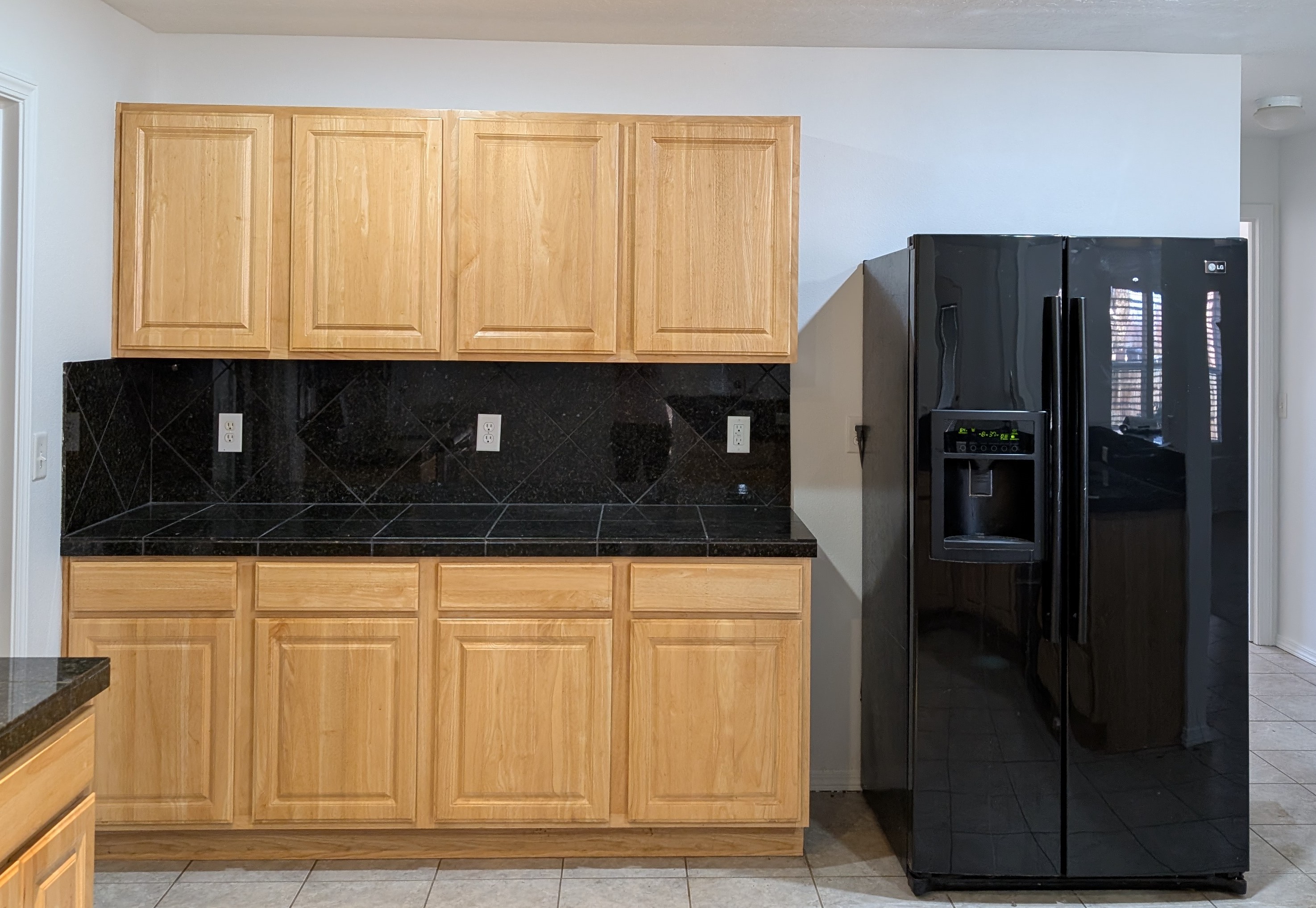 Dated kitchen with honey-oak cabinets and black diagonal tile counters before remodel