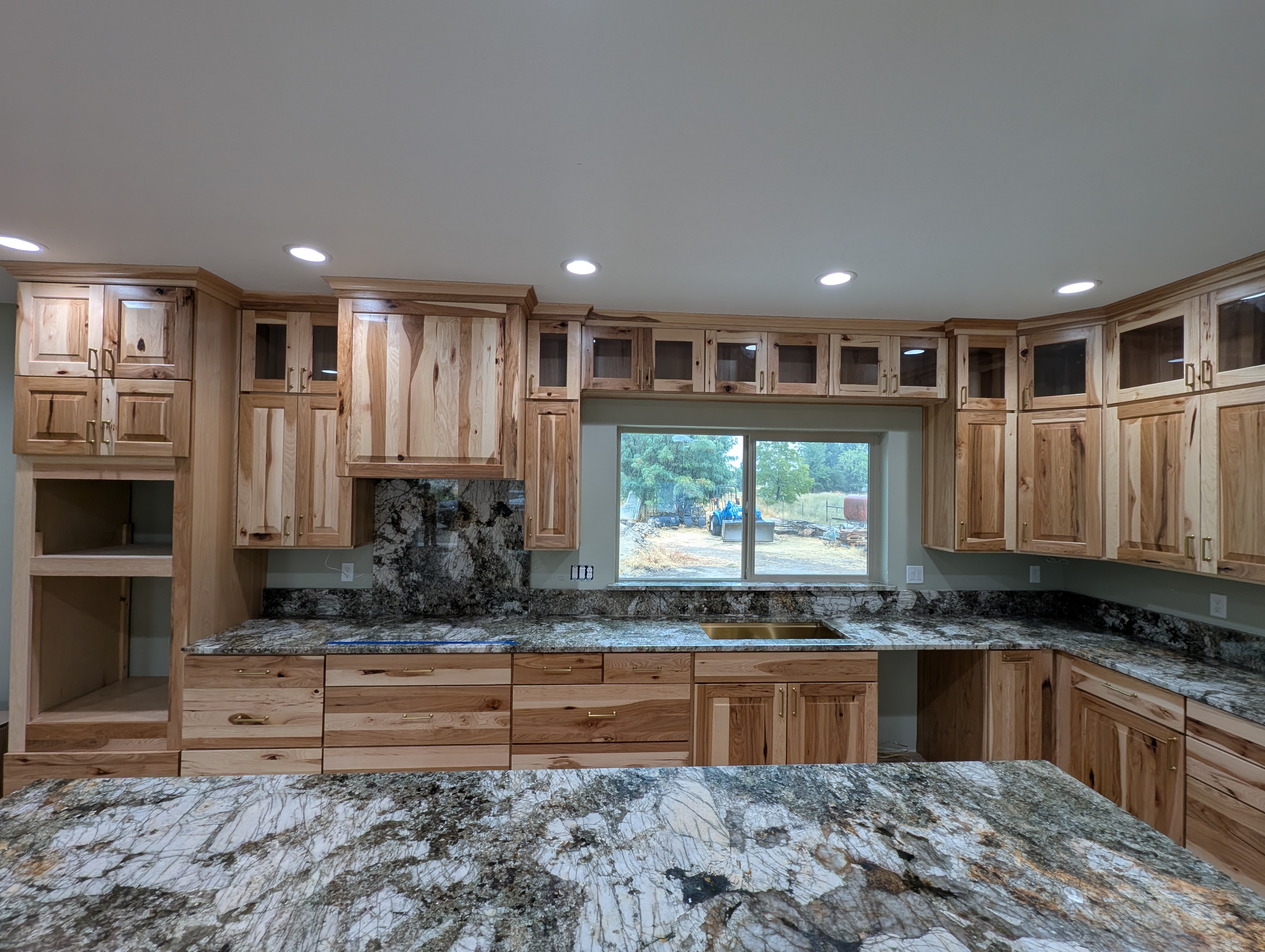 Remodeled hickory kitchen with dramatic granite counters, glass-front uppers and gold hardware