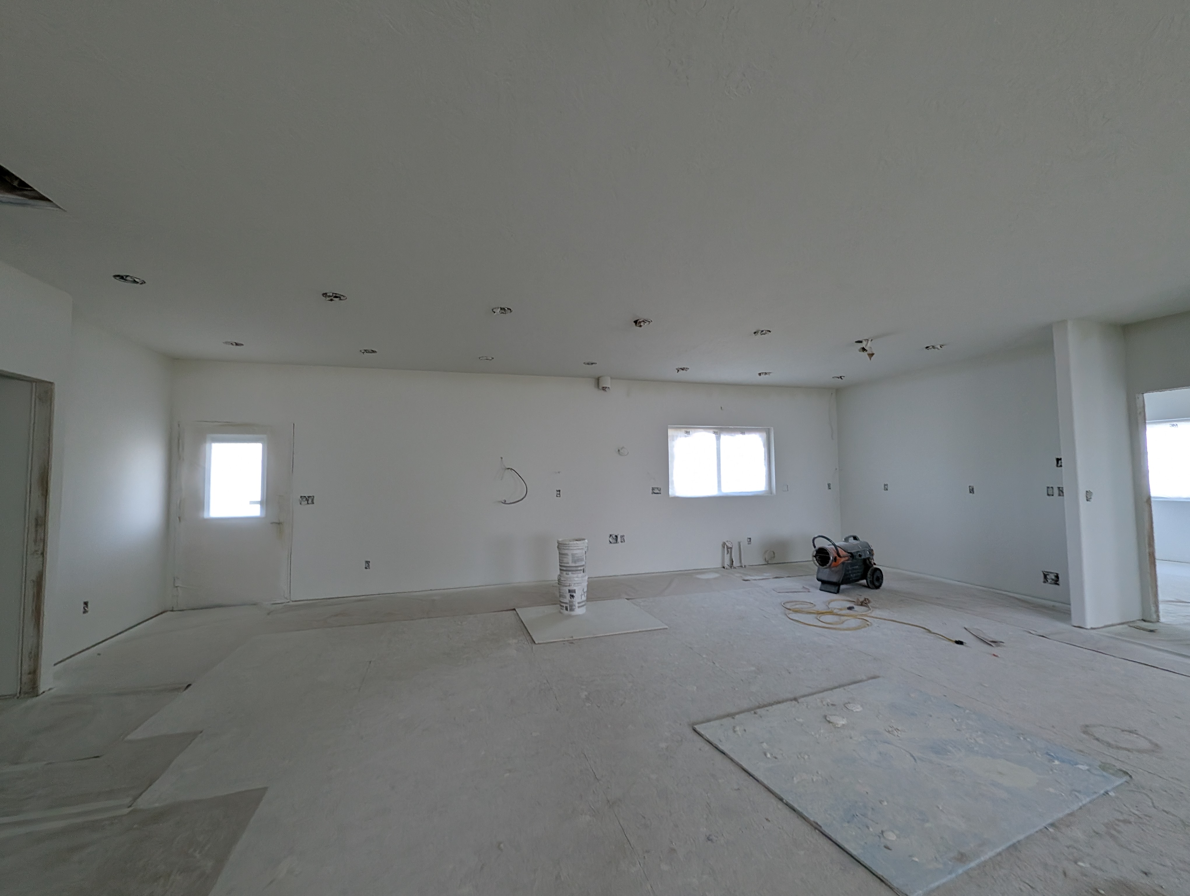 Gutted kitchen space with bare drywall and concrete floor before remodel