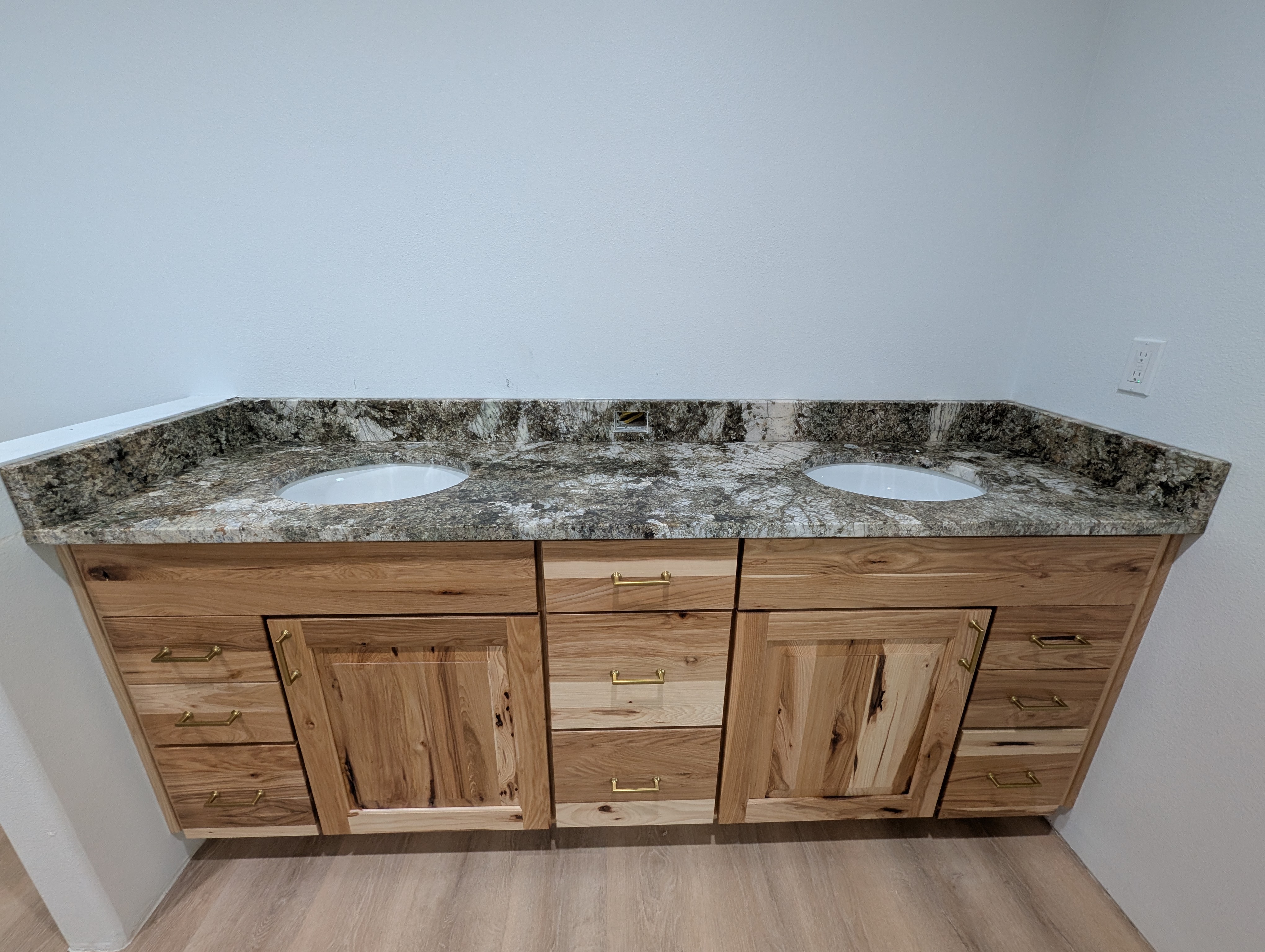 Remodeled hickory double vanity with dramatic granite countertop and gold hardware