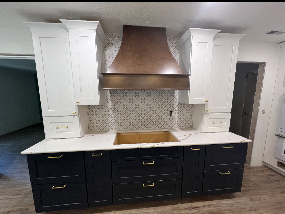 Remodeled kitchen with white and navy cabinetry, copper range hood and patterned tile backsplash