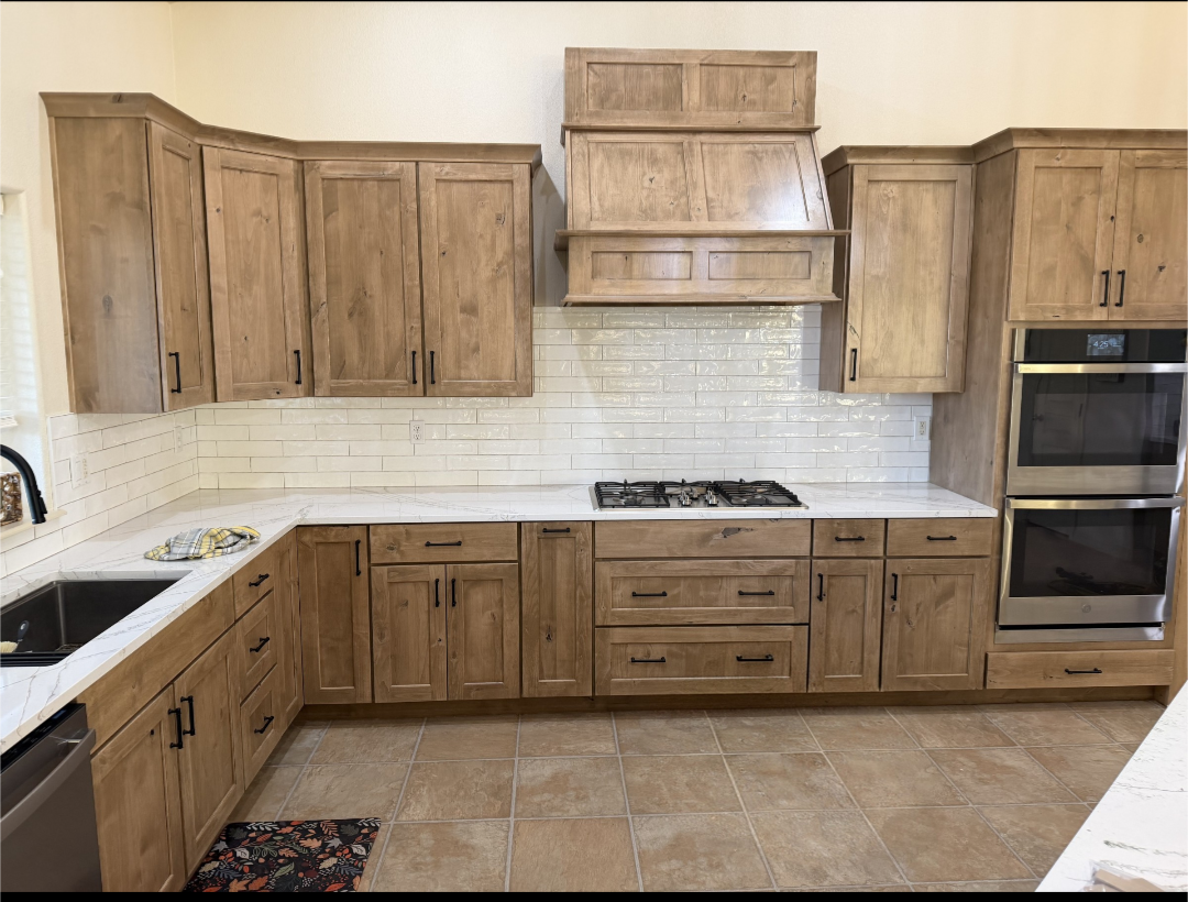Remodeled warm hickory kitchen with white subway tile, marble counters and custom wood range hood
