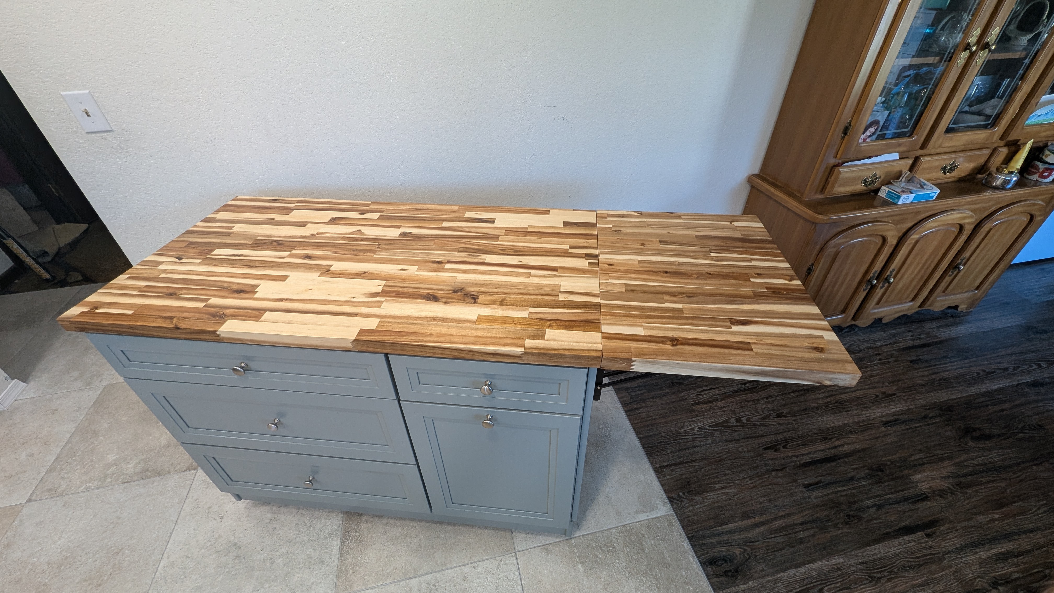 Gray kitchen island with its butcher-block top extended into a full dining leaf