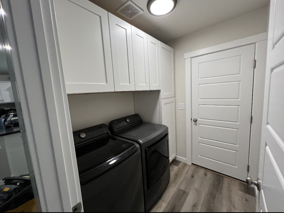 Laundry room with white upper cabinets, a tall pantry cabinet and wood-look floors